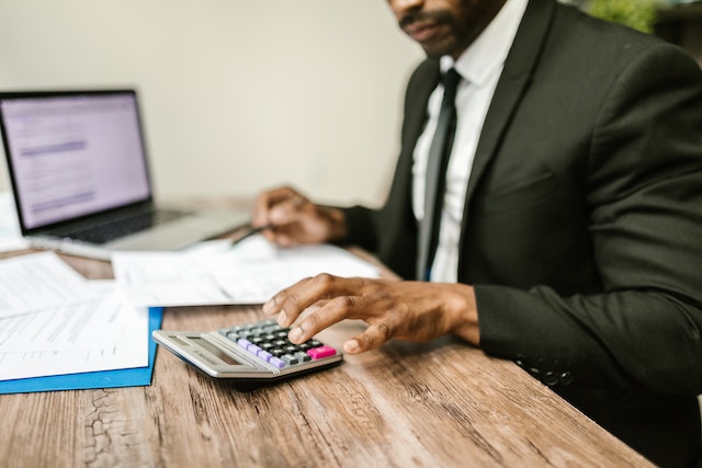 a person sitting at a desk looking over financial documents and using a calculator